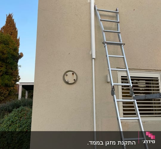 סולם ליד קיר עם צינור מיזוג אוויר